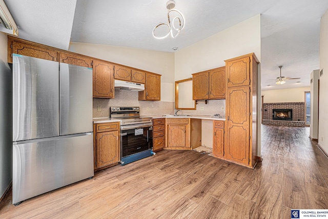 kitchen with a fireplace, sink, light hardwood / wood-style floors, and appliances with stainless steel finishes