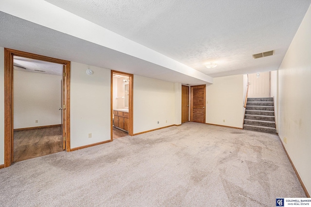 basement featuring light carpet and a textured ceiling