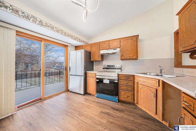 kitchen featuring appliances with stainless steel finishes, tasteful backsplash, vaulted ceiling, sink, and light hardwood / wood-style floors