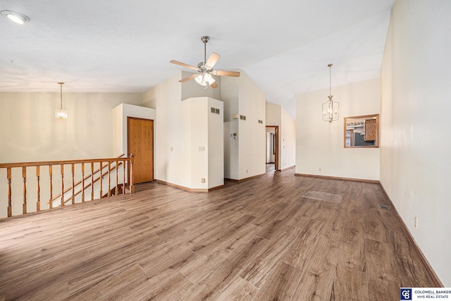 unfurnished living room with ceiling fan with notable chandelier, wood-type flooring, and lofted ceiling