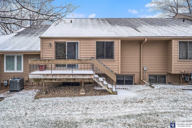 snow covered rear of property featuring central AC and a wooden deck