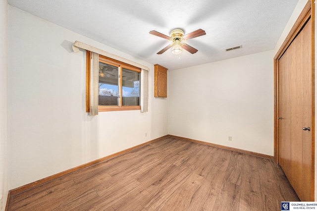 unfurnished bedroom featuring a closet, ceiling fan, light hardwood / wood-style flooring, and a textured ceiling