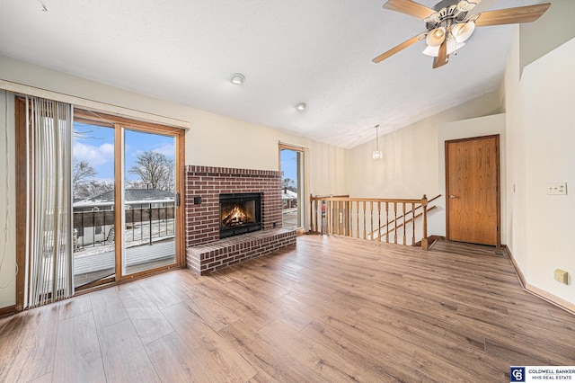 unfurnished living room with hardwood / wood-style flooring, plenty of natural light, lofted ceiling, and a fireplace