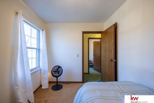 bedroom featuring light colored carpet and a textured ceiling