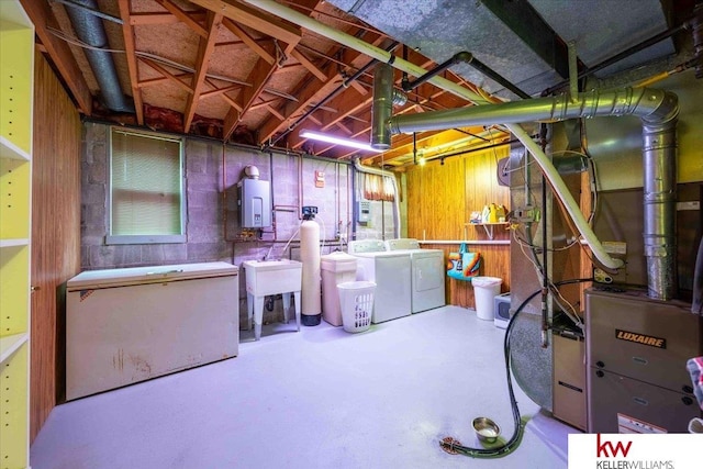 basement featuring refrigerator, sink, wooden walls, independent washer and dryer, and heating unit