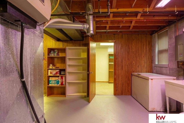 basement featuring refrigerator and wood walls