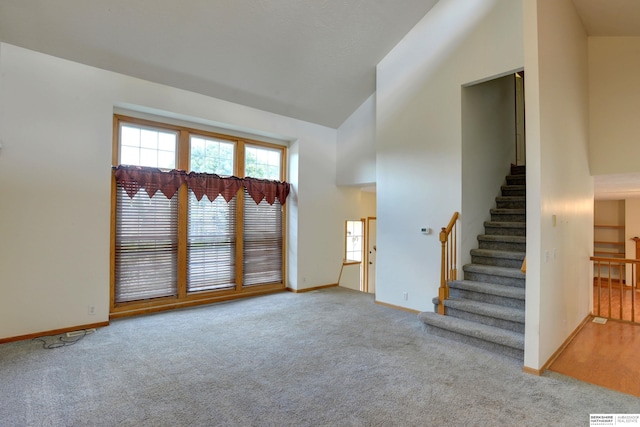 unfurnished living room featuring light carpet and high vaulted ceiling