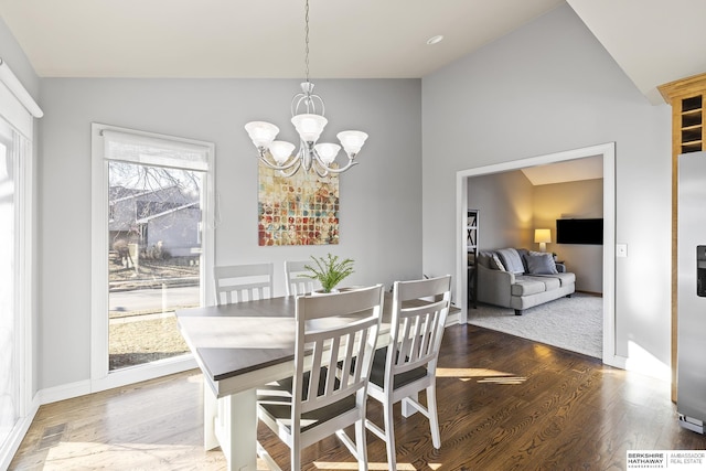 dining space featuring wood-type flooring, an inviting chandelier, and vaulted ceiling