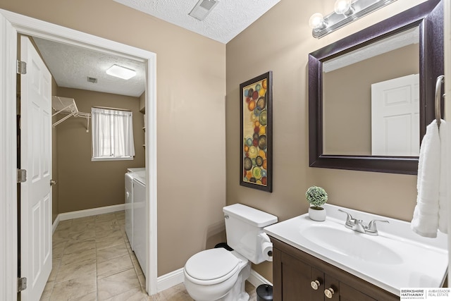 bathroom featuring a textured ceiling, independent washer and dryer, toilet, tile patterned floors, and vanity