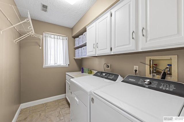 clothes washing area featuring a textured ceiling, cabinets, and independent washer and dryer