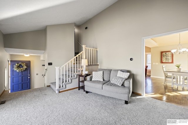 living room with a notable chandelier, high vaulted ceiling, and carpet floors