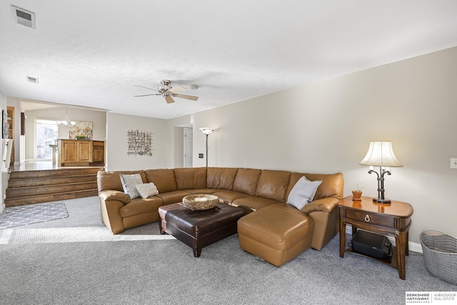 living room featuring a textured ceiling, light colored carpet, and ceiling fan with notable chandelier