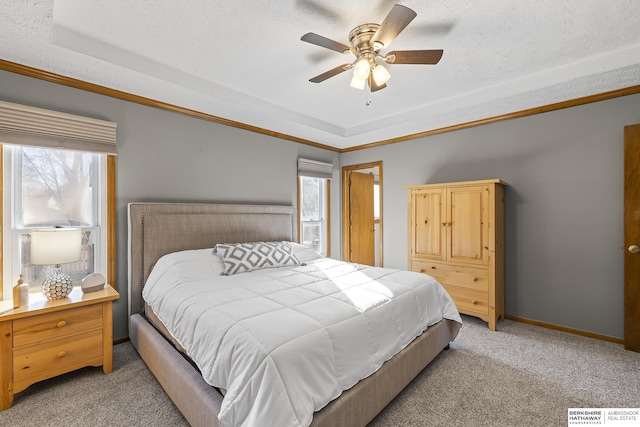 bedroom featuring ceiling fan, light colored carpet, multiple windows, and a tray ceiling