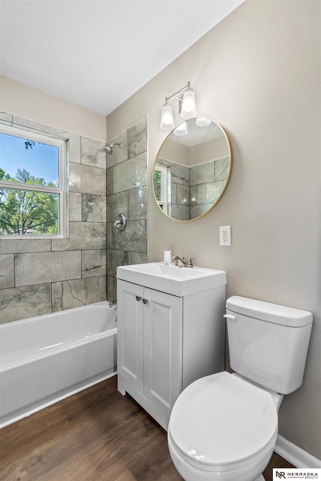 full bathroom with vanity, hardwood / wood-style flooring, toilet, and tiled shower / bath