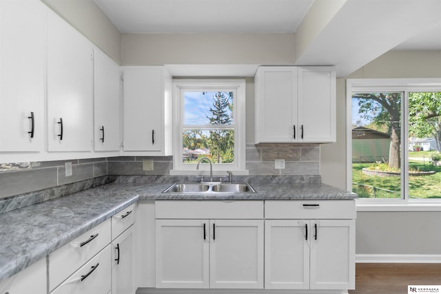 kitchen with dark hardwood / wood-style flooring, white cabinetry, sink, and tasteful backsplash