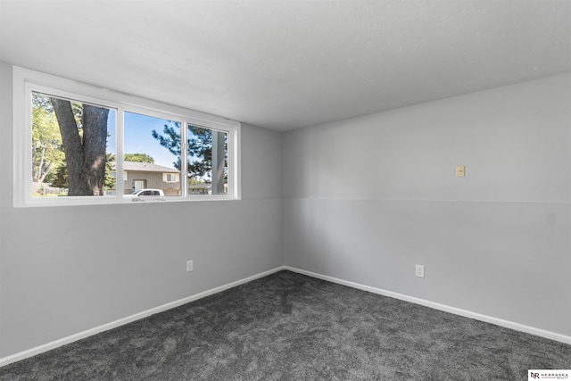 spare room featuring dark carpet