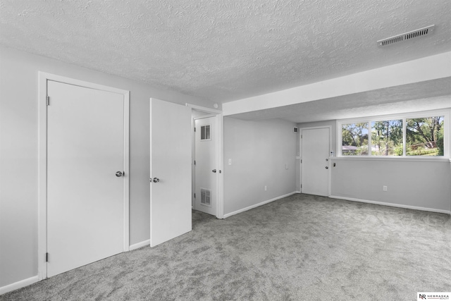 carpeted empty room with a textured ceiling