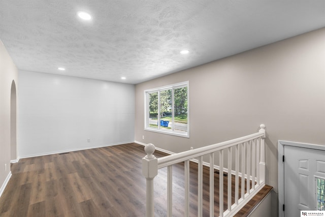 interior space with a textured ceiling and dark hardwood / wood-style floors