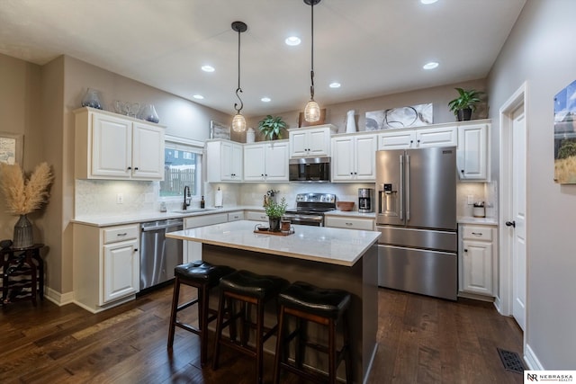 kitchen featuring stainless steel appliances, a kitchen island, white cabinetry, and sink