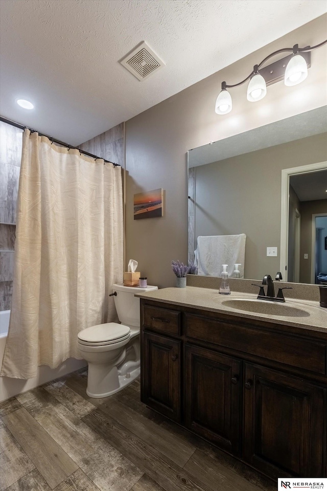 full bathroom featuring hardwood / wood-style floors, vanity, a textured ceiling, and toilet