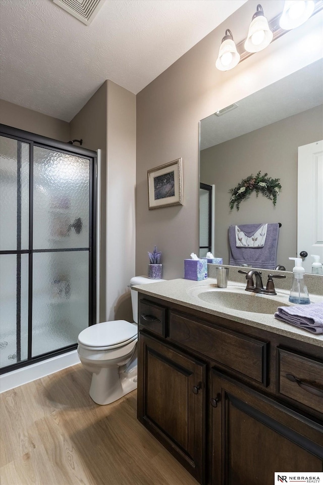 bathroom with toilet, a shower with door, vanity, and hardwood / wood-style flooring