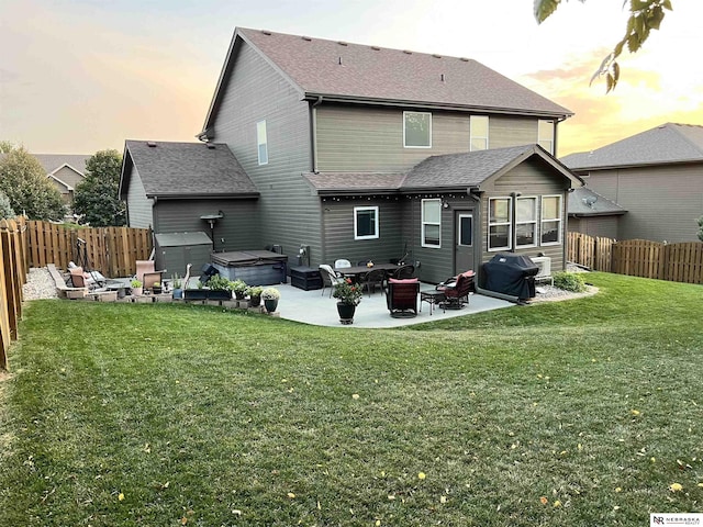 back house at dusk with an outdoor living space, a yard, a patio, and a hot tub