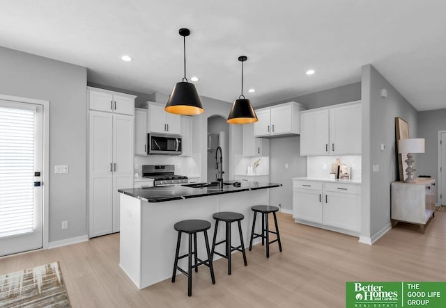 kitchen with white cabinets, stainless steel appliances, tasteful backsplash, and a kitchen island with sink