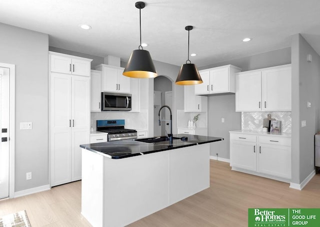 kitchen with backsplash, sink, an island with sink, appliances with stainless steel finishes, and white cabinetry