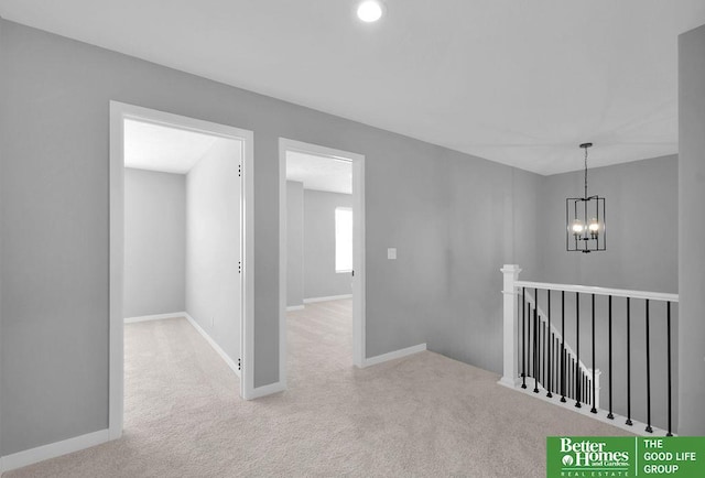 hallway with light carpet and an inviting chandelier