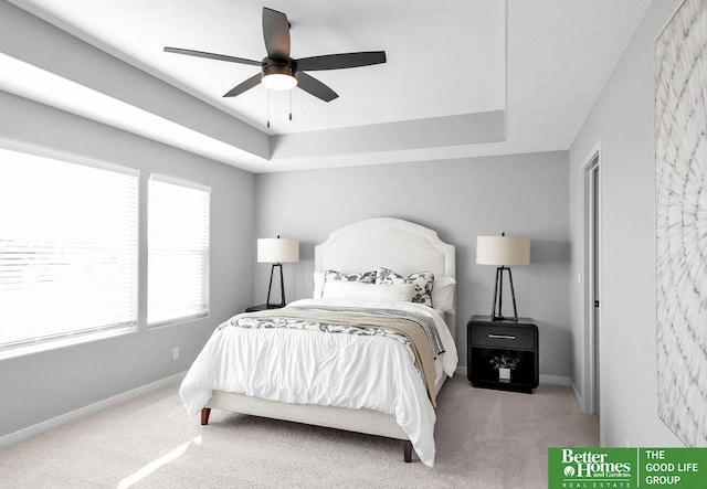 bedroom featuring carpet, a tray ceiling, and ceiling fan