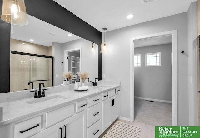 bathroom featuring a shower with door and vanity