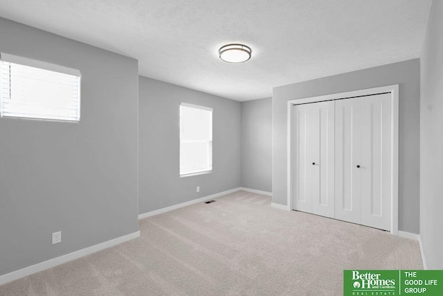 unfurnished bedroom with light carpet and a closet