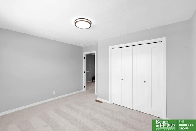 unfurnished bedroom featuring light colored carpet and a closet