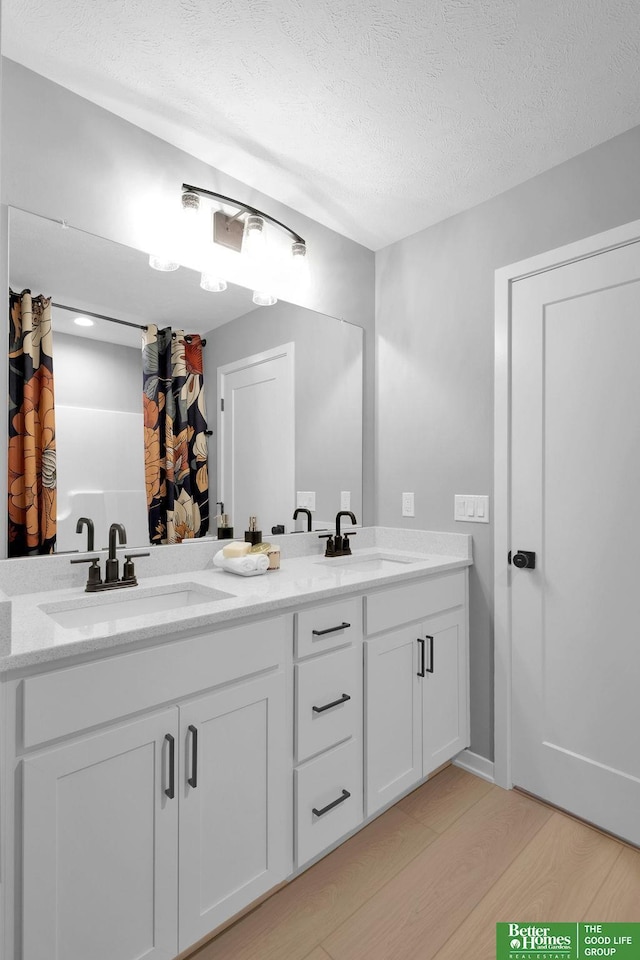 bathroom with hardwood / wood-style floors, vanity, and a textured ceiling