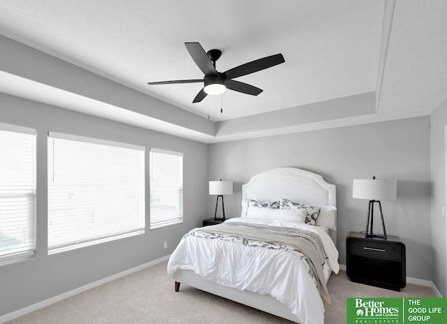 carpeted bedroom featuring ceiling fan and a tray ceiling