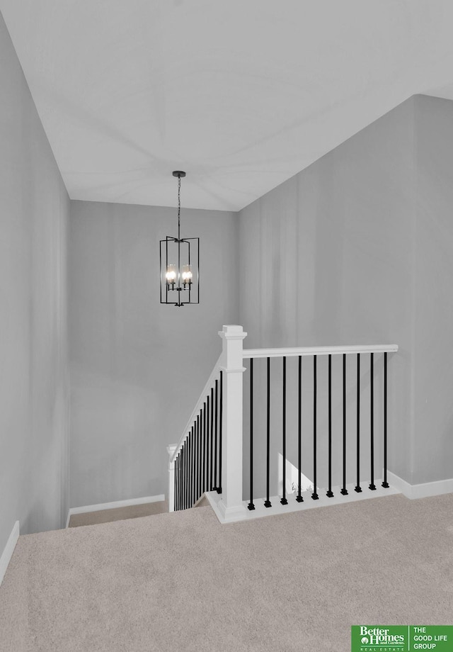 stairway with carpet flooring and a notable chandelier