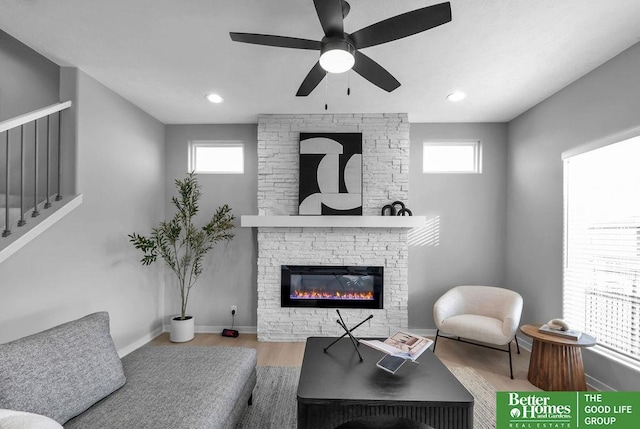 living room with a stone fireplace, ceiling fan, plenty of natural light, and hardwood / wood-style floors