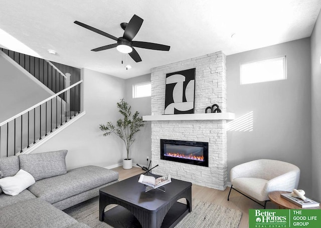 living room featuring ceiling fan, a fireplace, and light hardwood / wood-style floors