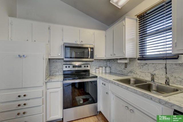 kitchen with white cabinetry, backsplash, appliances with stainless steel finishes, and vaulted ceiling