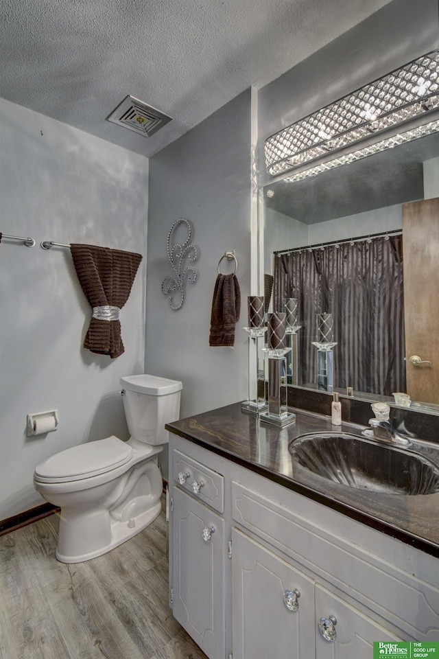 bathroom with hardwood / wood-style floors, vanity, a shower with curtain, toilet, and a textured ceiling