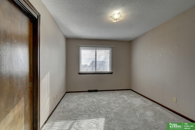 empty room with a textured ceiling and light carpet