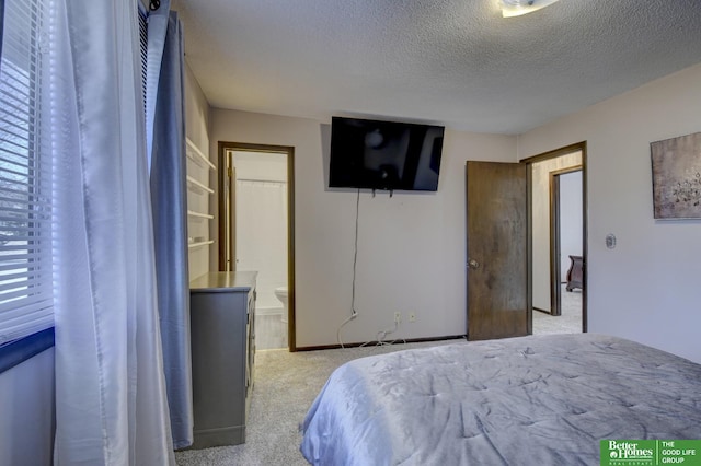 bedroom with a textured ceiling, ensuite bathroom, and light carpet