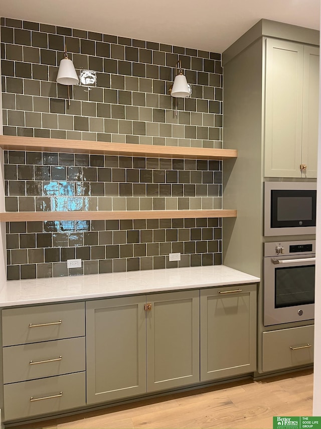 kitchen featuring light hardwood / wood-style floors, built in microwave, gray cabinetry, and stainless steel oven