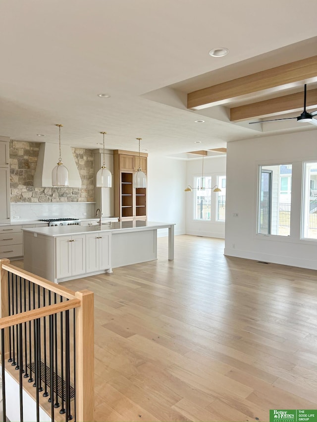 unfurnished living room featuring ceiling fan, sink, and light wood-type flooring