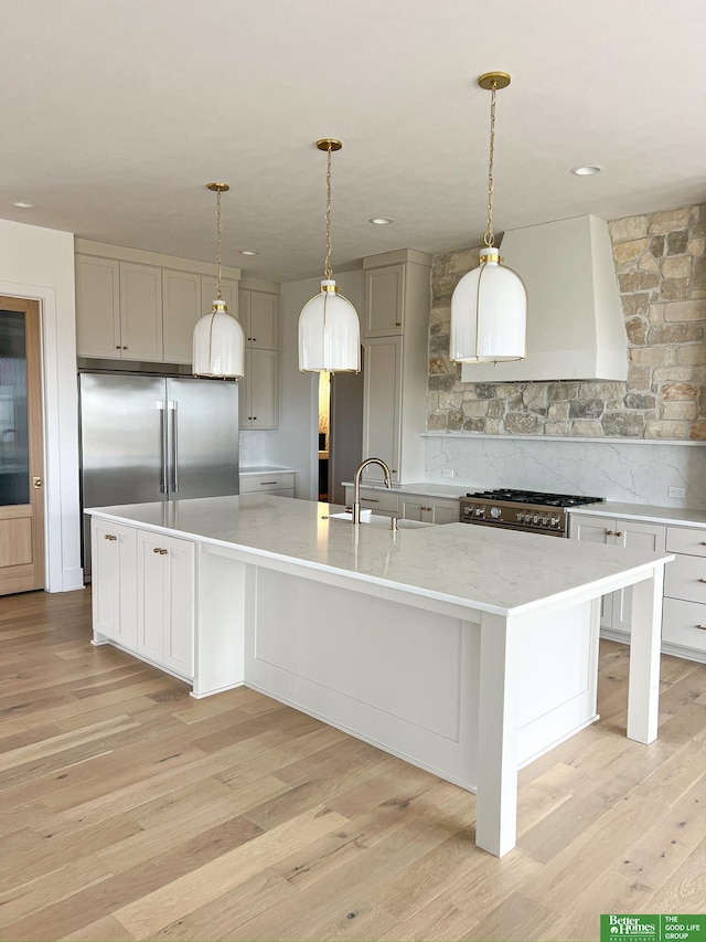 kitchen featuring light wood-type flooring, tasteful backsplash, stainless steel appliances, a spacious island, and exhaust hood