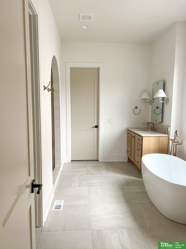 bathroom with tile patterned flooring, vanity, and a tub