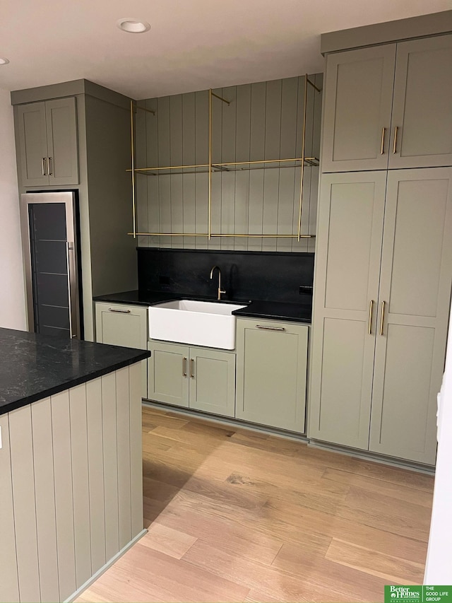 kitchen featuring light wood-type flooring, tasteful backsplash, stainless steel refrigerator, and sink