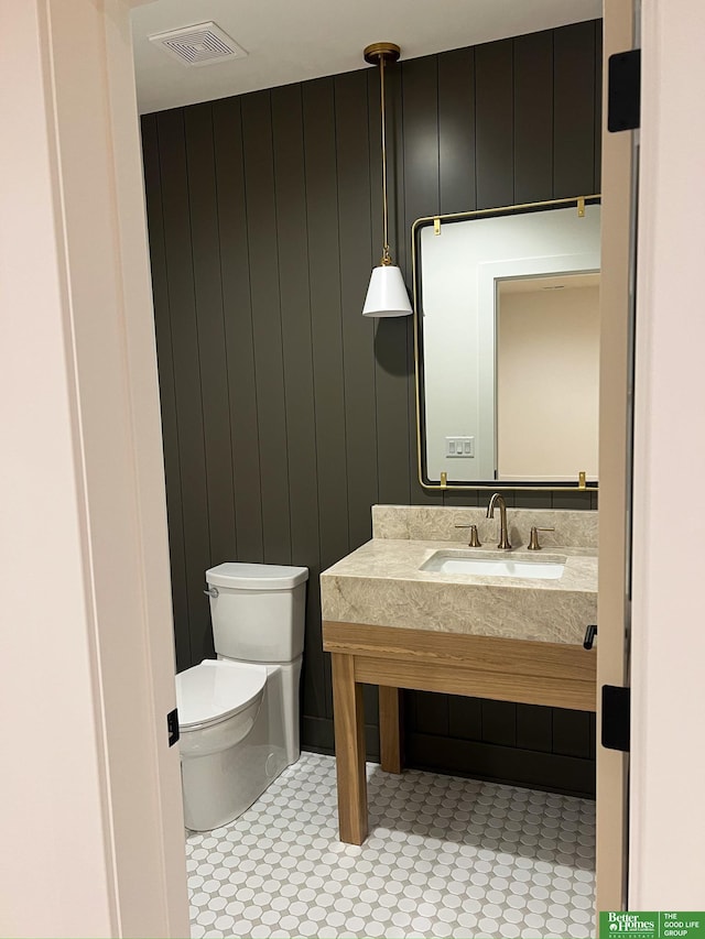 bathroom with tile patterned floors, wood walls, sink, and toilet