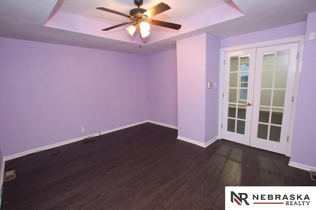 spare room featuring french doors, a raised ceiling, ceiling fan, and dark wood-type flooring