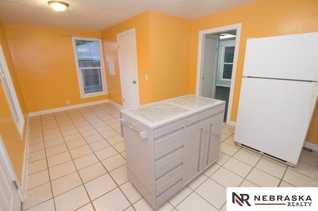 kitchen with white fridge, white cabinetry, a textured ceiling, and light tile patterned floors